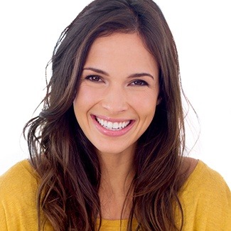 Woman wearing orange sweater smiling after getting veneers from Dallas cosmetic dentist