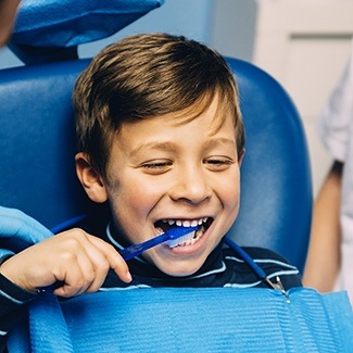Child brushing their teeth in dental chair