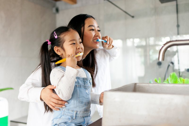 parent showing child how to brush teeth