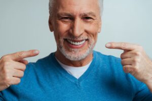 Patient pointing to his dentures and smiling