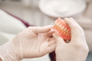 White gloved hands holding a full set of dentures